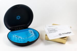 Top-down view of Invisalign clear aligner resting in a blue protective case with branded cleaning crystals, prepared for patient at Macquarie Fields dental practice.